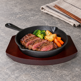 NTP-08 cast iron steak pan on dark serving base — steak and vegetables serving suggestion