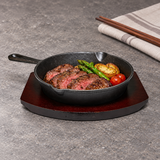 NTP-09 cast iron steak pan on dark serving base — steak and vegetables serving suggestion