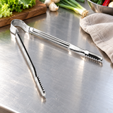 Stainless-steel serrated BBQ tongs on a restaurant prep counter