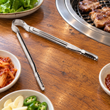 Stainless-steel serrated BBQ tongs on a restaurant table
