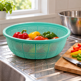 Green L1 colander draining peppers and tomatoes beside separate preparation tools