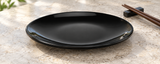 Empty M0016-BK glossy black round melamine plate on a stone table