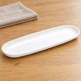 White elongated oval melamine dish in a natural tabletop setting