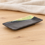 Dark brown and green rectangular ceramic dish in a natural tabletop setting