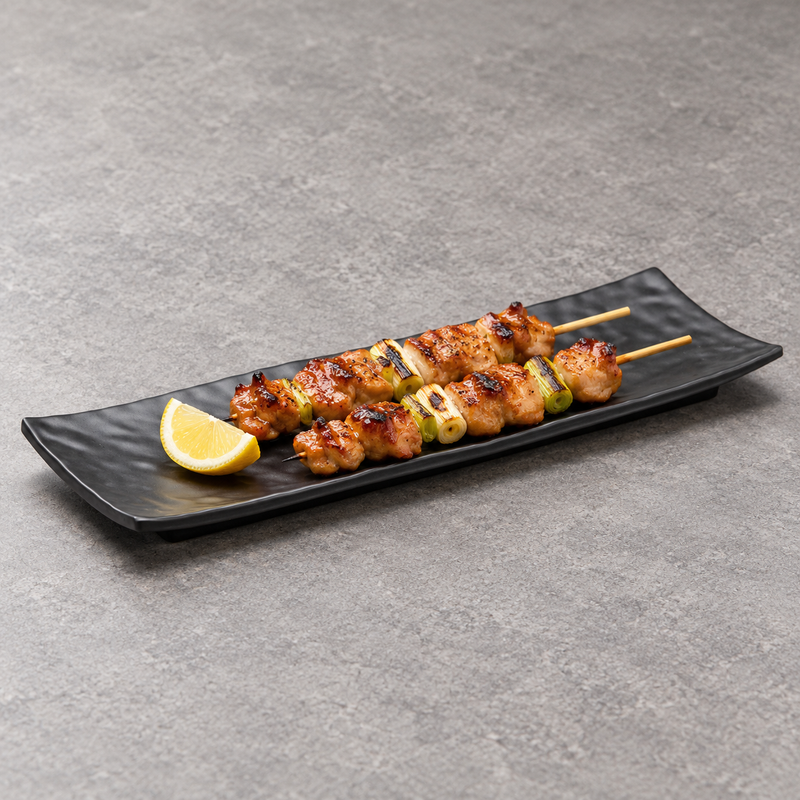 Matte black ripple platter with two small grilled skewers and a lemon wedge.