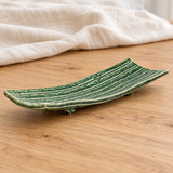 Green footed ceramic serving plate in a natural tabletop setting