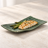 Green ridged rectangular ceramic plate with grilled fish and asparagus