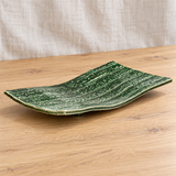 Green footed rectangular ceramic plate in a natural tabletop setting