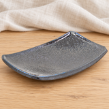 Dark gray and blue rectangular ceramic dish in a natural tabletop setting