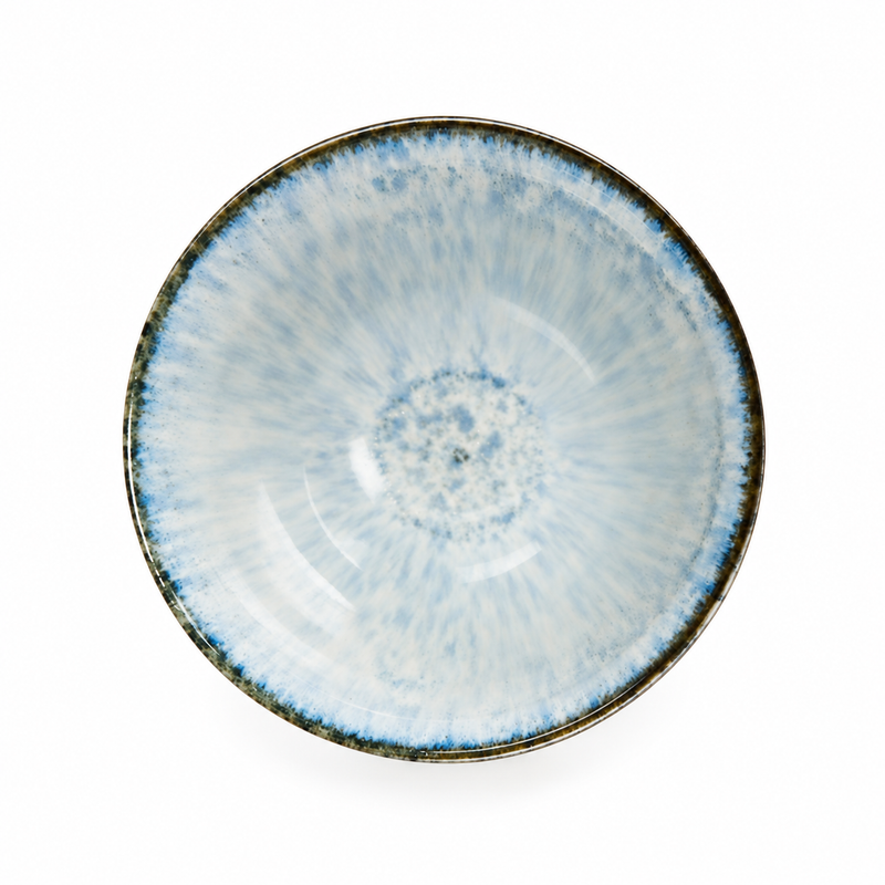 Overhead view of a pale blue and white ceramic bowl with radial mottling and a narrow dark rim.