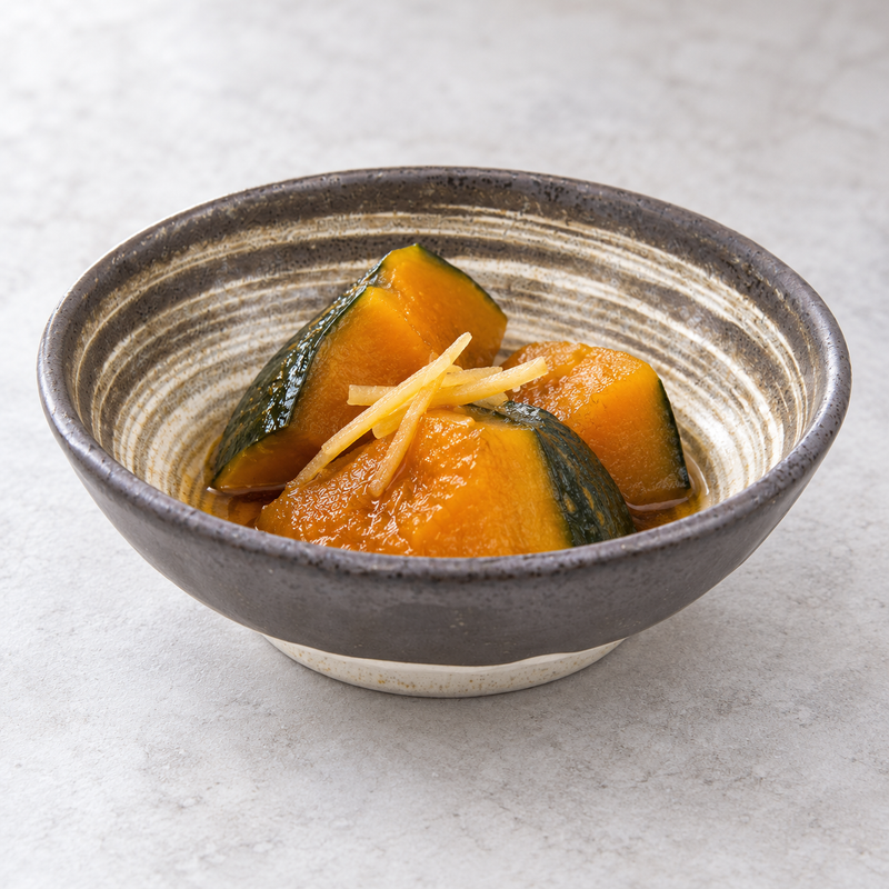 Low brown and beige spiral bowl holding orange squash pieces with dark green skin and a pale garnish.
