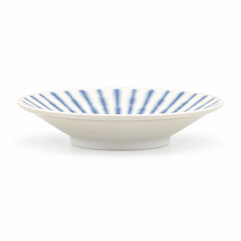 Low white ceramic bowl with fine blue radial interior stripes, a plain pale exterior and a small circular foot.
