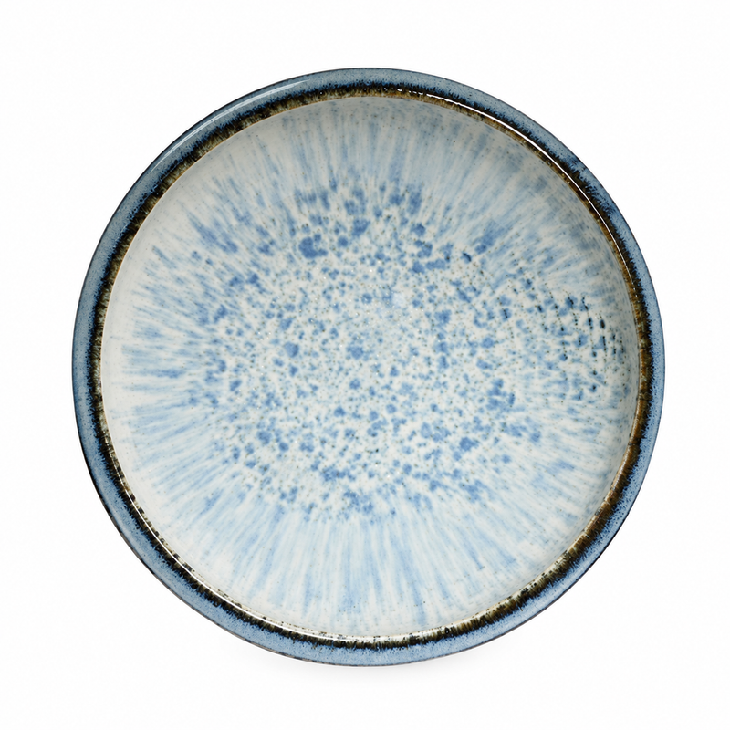 Overhead view of a wide white bowl with pale blue mottling, radiating interior marks and multiple blue-gray rim bands.