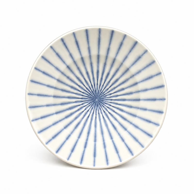 Overhead view of a pale beige round ceramic bowl with fine blue stripes radiating from the center to the rim.