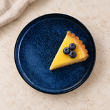 Blue round plate with a lemon tart slice and blueberries