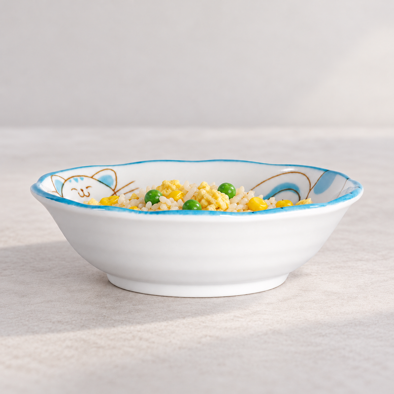 Blue cat-pattern ceramic bowl containing white rice, yellow egg pieces, corn kernels and green peas; no utensil is shown.
