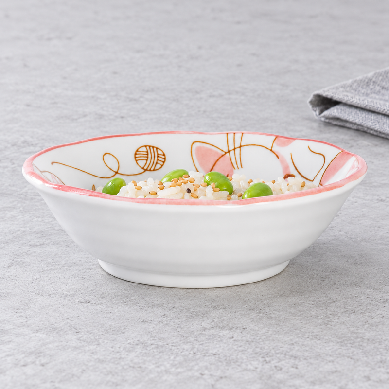 Pink cat-pattern ceramic bowl with white rice, plump green beans and tan seeds; a gray cloth sits behind it at the upper right.