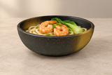 Black and gold bowl with shrimp udon