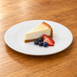 White broad-rim porcelain dinner plate with cheesecake and berries