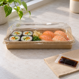 PH-07 kraft sushi tray with clear lid holding a lunch assortment on a light table