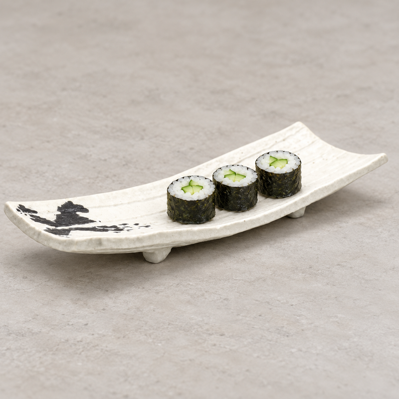 White elongated porcelain plate with raised ends and black end decoration, holding three cucumber, rice and nori rolls.