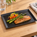 Black rectangular melamine plate with a salmon main course on a light oak table