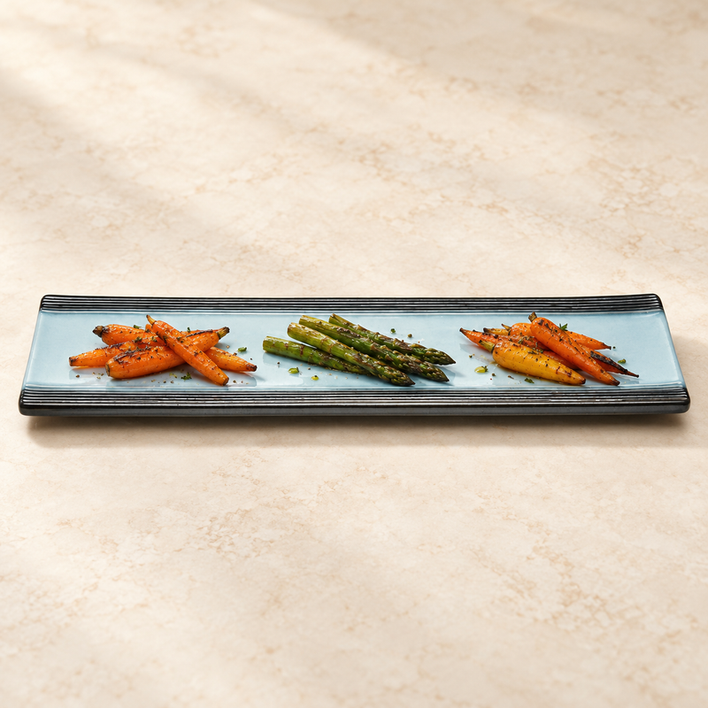 Long blue and black porcelain platter with three separate portions of vegetables