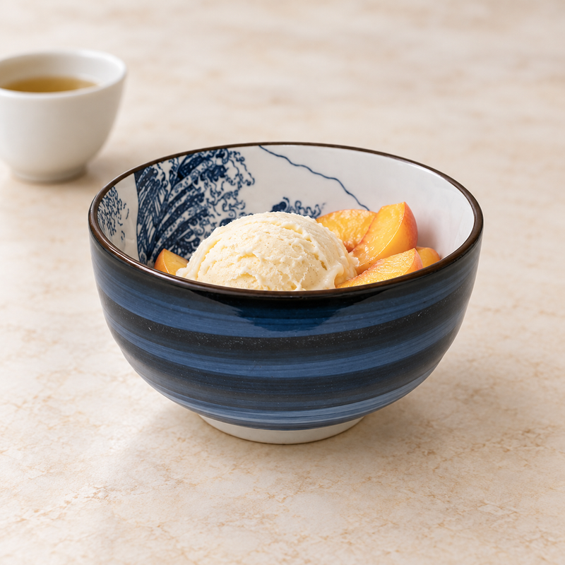 SH55-H ceramic bowl with a pale creamy scoop and orange-yellow red-skinned fruit slices, beside a separate pale cup of golden liquid at the upper left.