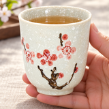 TC46 pink cherry blossom porcelain cup held with amber tea