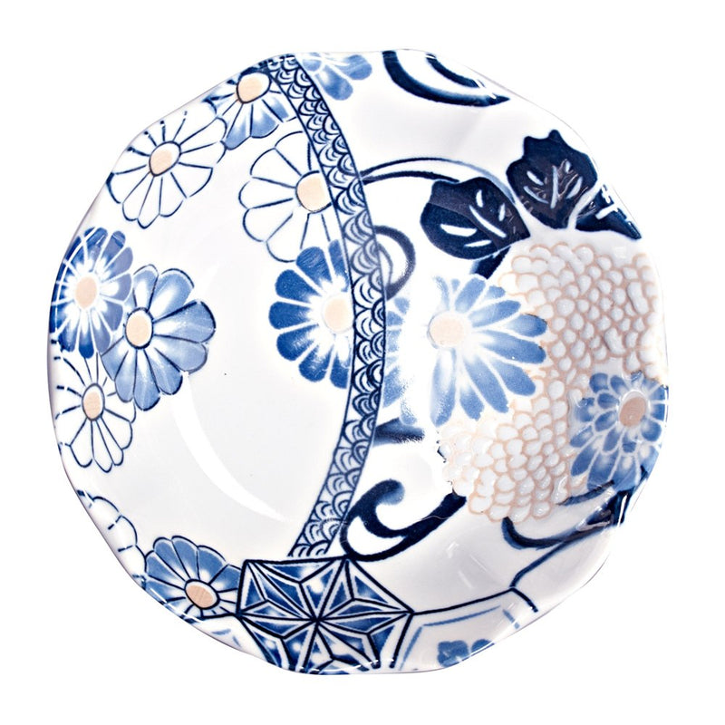 Overhead view of the shallow blue floral bowl, with blue blossoms, dark leaves, pale peach accents and a curved decorative band.