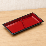 Red and black divided dish in a natural tabletop setting