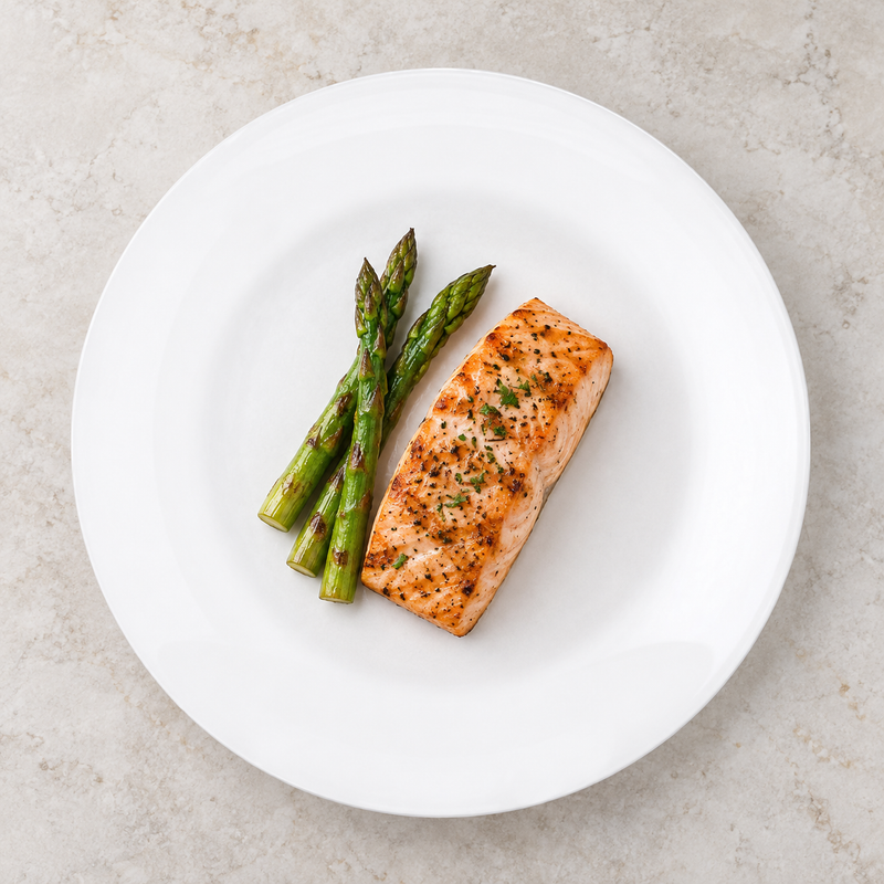 White round ceramic plate with salmon and asparagus