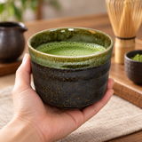 YK536-GB dark speckled ceramic matcha bowl with olive-green rim held with prepared matcha