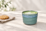 YK536-GR: Matcha latte with an oat biscuit in an airy stone-table setting.
