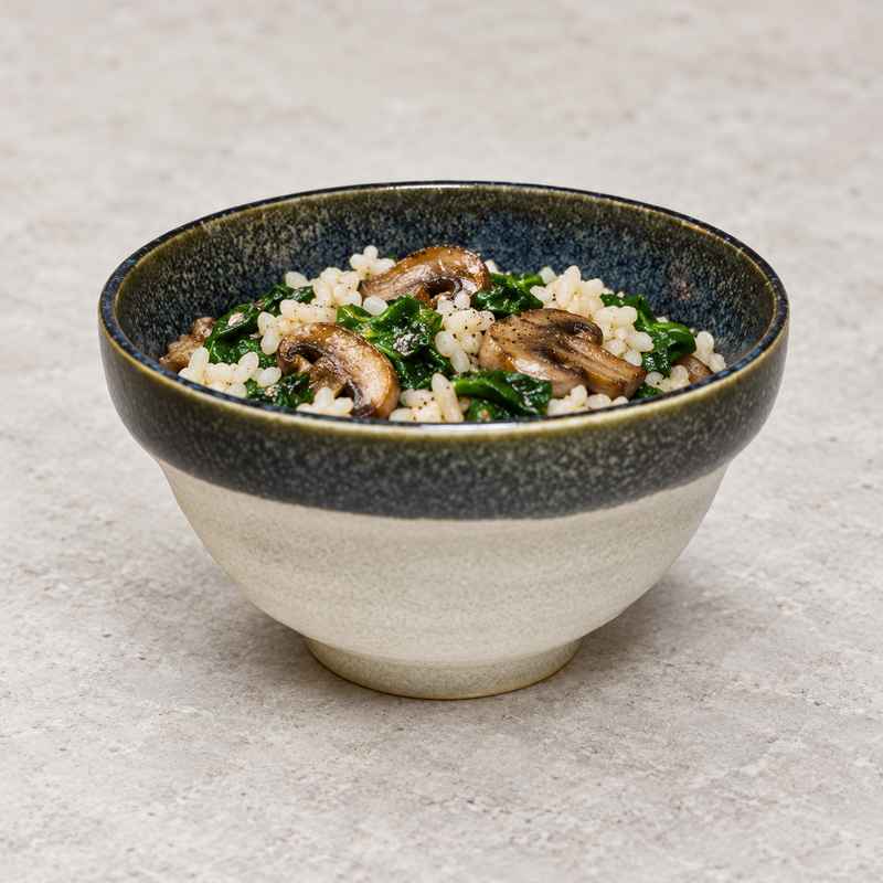 Dark-rim cream ceramic bowl filled with rice, sliced mushrooms and green vegetables.