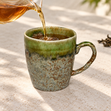 YT72-1 olive-green and mottled ceramic mug receiving tea from a separate server