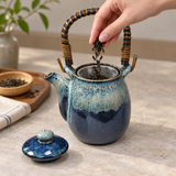 YW64-NU blue ceramic teapot with its lid removed while tea leaves are added to its mesh infuser