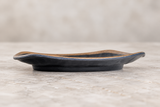 Side view of dark melamine plate with brown rim on a stone tabletop