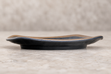 Side view of dark melamine plate with brown rim on a stone tabletop