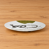 Oblique view of white melamine round plate with olive accents on wood