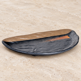 Oblique view of dark half-round melamine plate with orange accent on stone