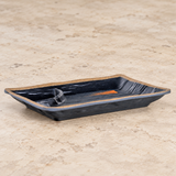 Oblique view of dark divided melamine plate with tan rim on stone