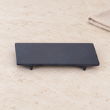 Black rectangular footed melamine plate on stone
