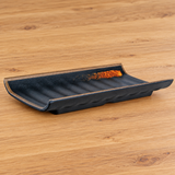 Dark melamine plate with raised edges and orange accent on a tabletop
