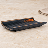 Dark melamine plate with raised edges and orange accent on a tabletop
