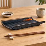 Black ribbed rectangular tray with warm accent, tea and chopsticks