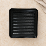 Black square melamine plate with ridged base on a tabletop