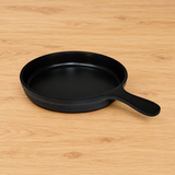 Black round melamine serving plate with handle on a tabletop