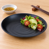 IT-Y7007B 7¼-inch black round ripple melamine plate with a small side salad