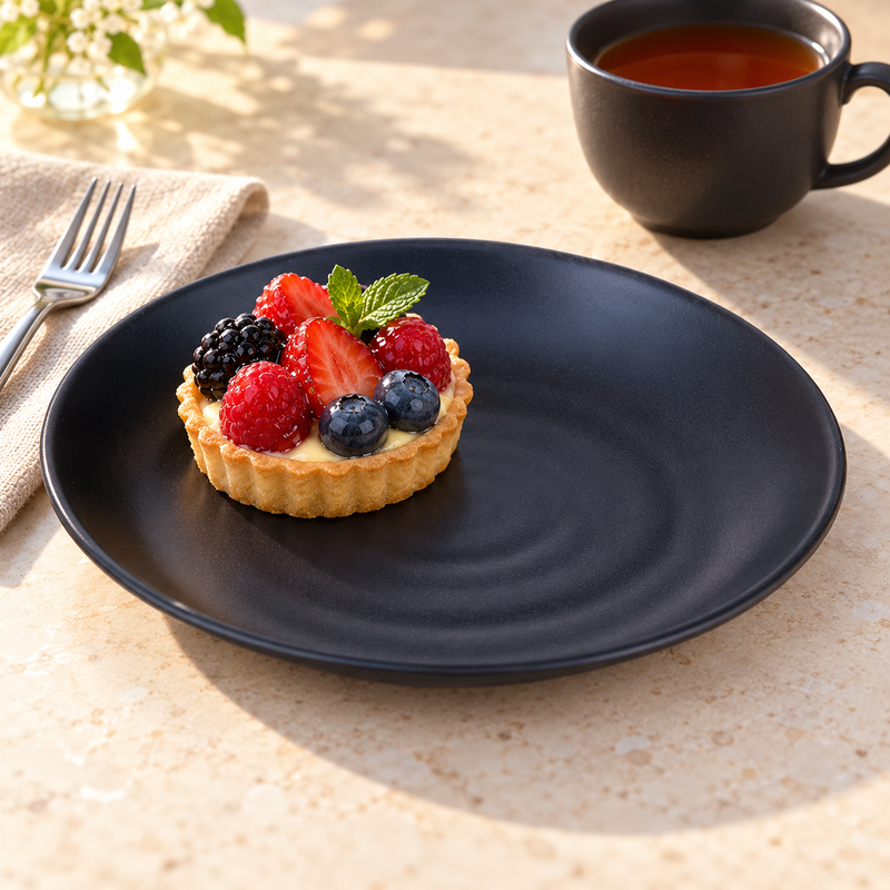 IT-Y7007B 7¼-inch black round ripple melamine plate with a berry tart